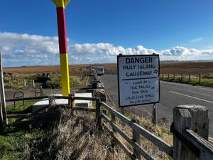 Causeway sign, it reads Danger Holy Island Causeway. Look at tide tables for safe crossing times. 30 yds ahead.